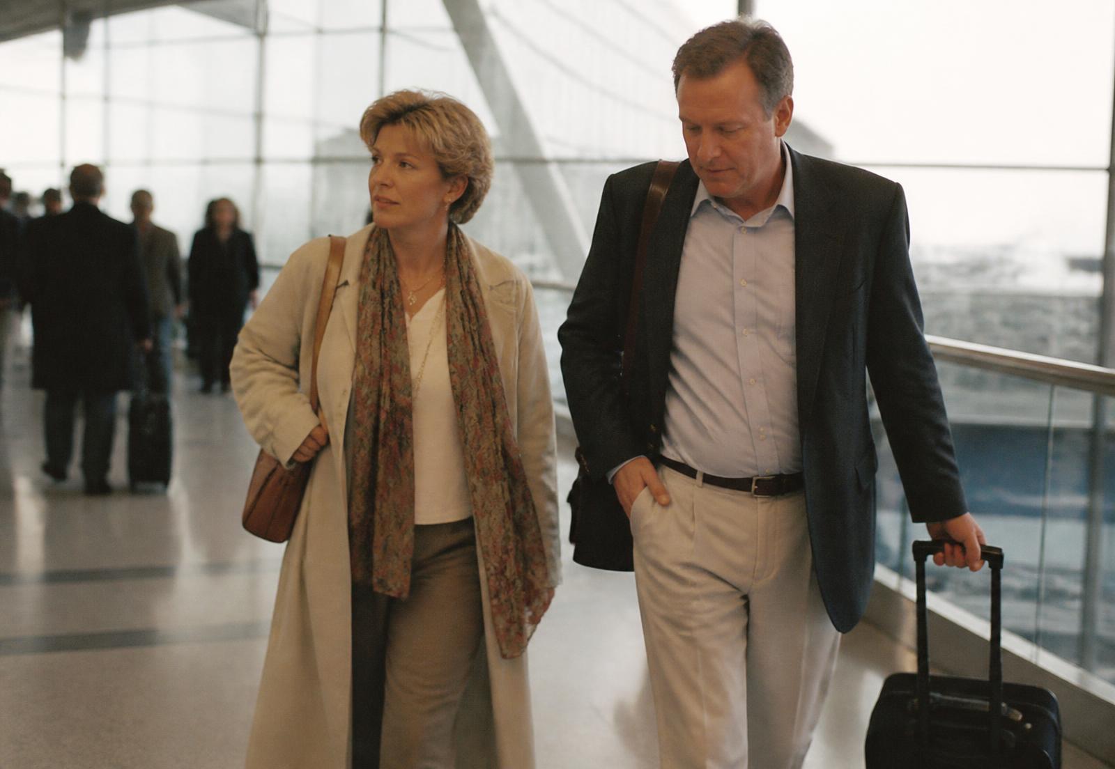 A couple walking through an international airport terminal with hand luggage